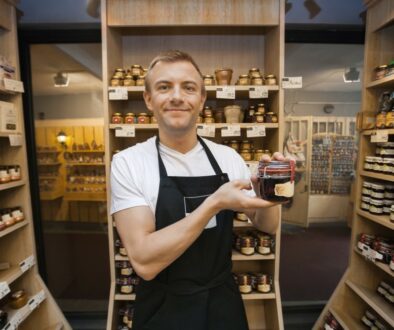 Think like a customer - Portrait of mid adult salesman holding jar of jam in grocery store